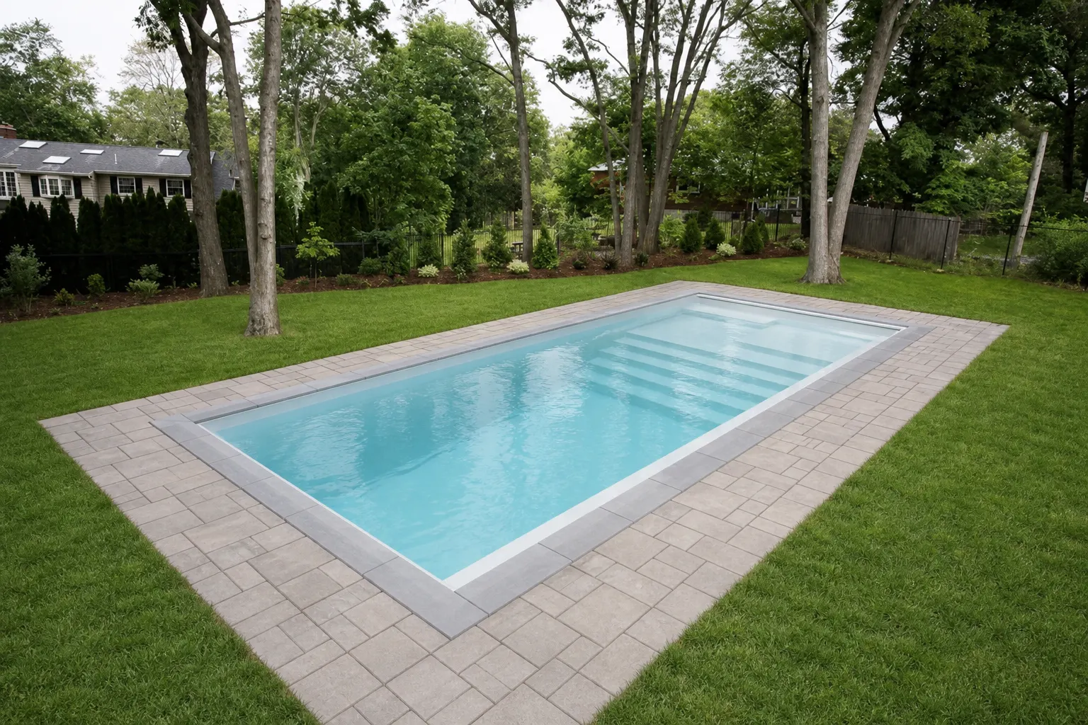 Finished fiberglass pool with paver patio in a Toronto backyard